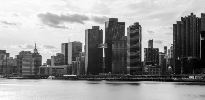 Black and white cityscape with tall buildings and water.